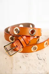 Cinto de cuero color whisky con hebilla metálica dorada y ojales metálicos dorados.