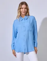 Camisa celeste con bordado sutil, cuello con solapa, abertura central con botones y bolsillo aplicado en el pecho.