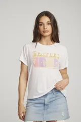 Remera blanca de algodón con estampa frontal de los rostros de los integrantes de The Beatles y el nombre de la banda en letras doradas.