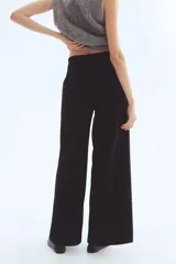 Pantalón negro de tiro alto con elástico oculto en la cintura. Presenta piernas anchas y rectas con pinzas y pliegues marcados tanto en la parte delantera como trasera.