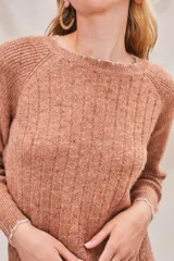 Sweater de punto color salmón con cuello redondo y mangas raglán.