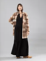 Vestido largo negro con escote en V y detalle de frunces en los hombros. Tiene mangas largas con elástico en los puños y volados en el ruedo.