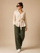 Camisa de seda color celeste, con cuello camisero, mangas largas y lazo ajustable en la cintura que genera un efecto fruncido.