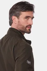 Campera liviana de color verde grisáceo, con cierre frontal, cuello alto y puños elásticos. Presenta un pequeño parche con logo en el pecho.