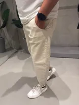 Jean de corte slouchy en color beige, confeccionado en denim de algodón. Presenta un diseño de tiro medio con ajuste holgado en la cadera y muslos, estrechándose hacia los tobillos.