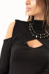 Polera negra de manga larga con diseño de hombros descubiertos y cuello alto. Presenta un recorte frontal en el pecho que crea un efecto de superposición.
