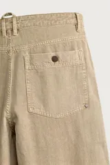 Pantalón relaxed fit de color beige, confeccionado en tejido con mezcla de algodón y lino, con diseño de cinco bolsillos, efecto lavado y cierre frontal con cremallera y botón.