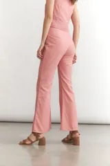 Pantalón de lino color rosado, tiro alto, con corte flare y costura central marcada en el frente de ambas piernas.