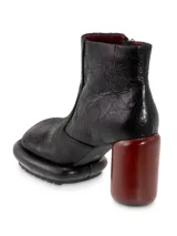 Botín de cuero negro con interior rojo, cierre lateral y tacón cilíndrico de madera color borgoña.