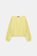 Sudadera de algodón con efecto lavado en color amarillo, cuello barco, abertura frontal con botones a presión y manga larga.