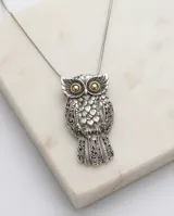 Dije con forma de búho elaborado en plata 925 con detalles en lámina de oro 18k en los ojos. Presenta un diseño detallado con texturas grabadas en las alas y el cuerpo.