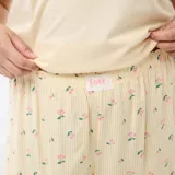 Pijama corto de dos piezas en color amarillo, compuesto por una camiseta lisa de manga corta con un pequeño estampado en el pecho y un short con patrón a rayas verticales y estampado de cerezas.