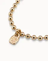 Pulsera de bolitas de metal bañado en plata con dije de candado grabado con el logo de la marca.