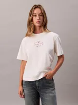 Remera boxy de algodón regenerativo en color blanco, con cuello redondo, manga corta y estampado gráfico con logo de Calvin Klein en el pecho.