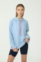Buzo hoodie celeste de rústico, con capucha y cordones de ajuste color salmón y verde. Tiene etiqueta de la marca en la manga derecha con logo Basset 00'S.