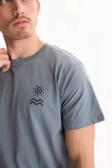 Remera gris de manga corta con pequeño estampado en el pecho que representa un sol y olas.