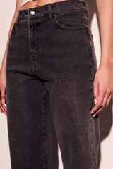 Pantalón de jean negro con efecto gastado y pequeños brillos. Corte recto, tiro alto y terminación desflecada.