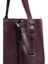 Cartera tipo saco Calvin Klein color borgoña, con correa larga regulable y logo CK plateado en el frente.