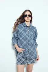 Sobrecamisa de jean con estampado de cuadros, corte relajado, cuello clásico y cierre frontal con botones metálicos.