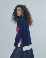 Sweater de tejido fino con cuello alto, diseño de bloques de color en azul marino, blanco y fucsia. Presenta el nombre de la marca estampado en la manga en color fucsia.