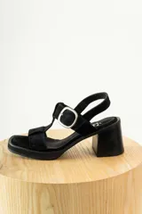 Sandalias de gamuza negra con taco cuadrado y plataforma. Presentan un diseño de tiras anchas con una hebilla metálica plateada ajustable en el lateral.