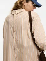 Camisa larga tipo vestido a rayas verticales color beige y blanco, con botones en la parte delantera y trasera.