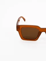 Lentes de sol con armazón cuadrado de acetato en color caramelo y cristales oscuros.