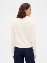 Buzo de tejido suave con cuello redondo, mangas largas y puños acanalados. Presenta un diseño de calce ajustado con terminación en el ruedo también acanalada.