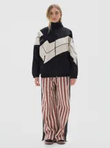 Campera de jean con diseño color block en negro y beige, corte oversized, cuello alto, cierre frontal y bolsillos laterales con cierre. Presenta detalles de costuras visibles y logo de la marca estampado en el pecho.