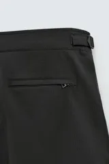 Bañador de hombre color negro, de largo medio, confeccionado en tejido técnico. Presenta cintura elástica ajustable con cordón interior, trabillas laterales, bolsillos frontales y bolsillo trasero con cierre de cremallera.