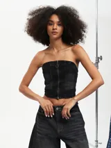 Top tipo corset confeccionado en denim negro, con escote strapless y cierre frontal con cremallera.