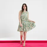 Vestido corto blanco con estampado floral en tonos verdes, azules y naranjas. Tiene cuello en V y corte evasé.