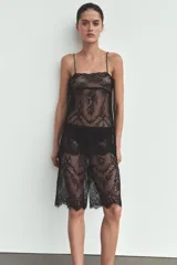 Pantalón capri semitransparente confeccionado en tejido de encaje con diseño floral. Presenta tiro alto y cintura elástica ajustable con lazada, con terminaciones festoneadas en el ruedo.