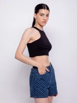 Short de jean azul con textura de roturas, tiro alto, cinco bolsillos, botón y cierre metálico.