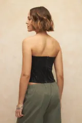 Top strapless negro con diseño tipo corset, de textil engomado y texturizado.