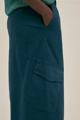 Falda larga azul petróleo estilo cargo con cintura regulable, tajo frontal, dos bolsillos laterales y un bolsillo con solapa.