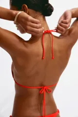 Top de bikini triangular color rojo, con relleno extraíble, tiras ajustables para atar en el cuello y la espalda, y detalle de cuentas en el frente.