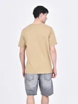 Remera de corte regular color tostado, con cuello redondo y estampa frontal con diseño de hojas y texto enmarcado.