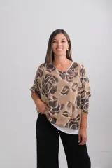Sweter de punto con diseño de doble capa, compuesto por una capa superior estampada con flores grandes en tonos tostado y marrón, y una capa inferior lisa de color blanco. Presenta cuello redondo, mangas tres cuartos y un corte holgado.