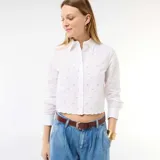 Camisa blanca de manga larga con diseño cropped, cuello camisero, cierre frontal con botones y detalles de bordados all over con perforaciones.