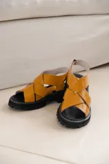 Sandalias de cuero color mostaza con tiras anchas cruzadas y suela track negra.