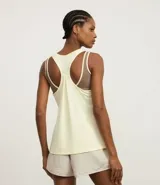 Musculosa deportiva de corte nadador, color amarillo claro, confeccionada en microfibra con textura perforada. Presenta escote en U y diseño holgado con pliegue en la espalda.