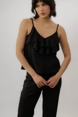 Musculosa negra con escote en V, breteles finos regulables y doble volado frontal con pespuntes.