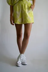 Short de lino y algodón color blanco con estampado de flores en verde lima, con elástico en la cintura y bolsillos laterales.