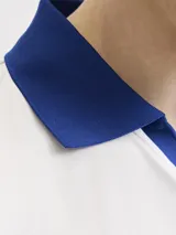 Camiseta de manga corta con cuello tipo polo en color azul, cuerpo en color blanco y calce relajado. Presenta estampados frontales con la leyenda 'FIFA WORLD CUP' y 'CAN MEX USA', junto con un parche conmemorativo del evento.