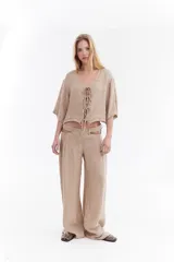 Blusa de lino italiano color beige, de manga corta, con escote en V y cierre frontal mediante lazos o moños.