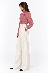 Blusa rosada de 100% lino natural, con cuello alto con volado, mangas largas abullonadas y cierre frontal de botones con detalles de volados en la cartera.