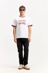 Remera marrón de manga corta confeccionada en algodón, con cuello redondo y ribetes en contraste de color tostado en el cuello y los puños. Presenta estampa frontal con la frase "your vibe attracts your tribe" y el logo de Mistral.