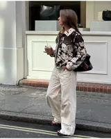 Campera con estampado de vaca en tonos marrón y blanco, de corte recto, con cuello camisero, cierre con botones a presión, bolsillos de parche en el pecho y bolsillos laterales.