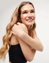 Pulsera dorada con cadena de bolitas y cierre de mosquetón. Incluye un dije circular con el logo de la marca.